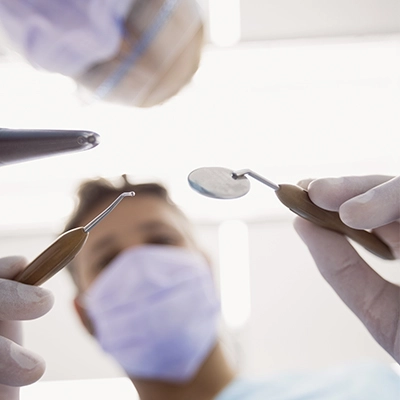 um dentista abrindo a boca do paciente para cirurgia odontológica