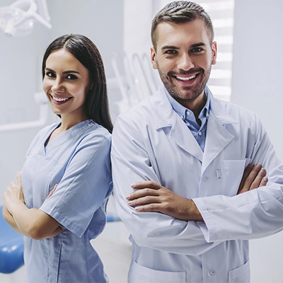 um homem e uma mulher de braços cruzados no consultório odontológico