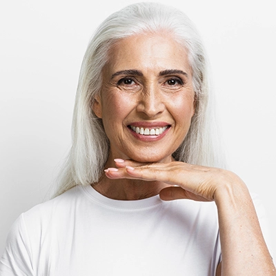 uma senhora de meia idade sorrindo com implantes dentários